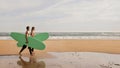 Happy young surfers couple with surfboards walking along the beach Royalty Free Stock Photo