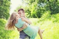 Happy young sweet couple is kissing, man and woman in love, he holds her on a hands at grass Royalty Free Stock Photo