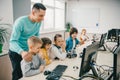 happy young teacher helping his teen students with diy robot on stem