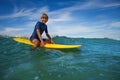 Happy young teen boy sit on orange surfboard in ocean Royalty Free Stock Photo