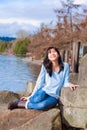 Happy young teen girl face upturned, smiling, while sitting outdoors on rocks along lake shore