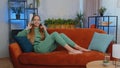 Happy young teen girl in wireless headphones relaxing lying on sofa at home listening favorite music Royalty Free Stock Photo