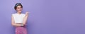 Happy young teen woman standing with her finger pointing isolated on purple background with copy spa Royalty Free Stock Photo