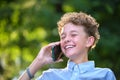 Happy young teenage boy talking on mobile phone outdoors in summer park. Online friendship concept Royalty Free Stock Photo