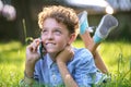 Happy young teenage boy talking on mobile phone outdoors in summer park. Online friendship concept Royalty Free Stock Photo