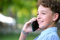 Happy young teenage boy talking on mobile phone outdoors in summer park. Online friendship concept Royalty Free Stock Photo