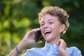 Happy young teenage boy talking on mobile phone outdoors in summer park. Online friendship concept Royalty Free Stock Photo