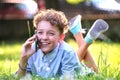Happy young teenage boy talking on mobile phone outdoors in summer park. Online friendship concept Royalty Free Stock Photo