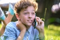 Happy young teenage boy talking on mobile phone outdoors in summer park. Online friendship concept Royalty Free Stock Photo