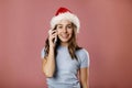 Happy young teenager girl in Santa claus hat talking on the phone, cheerful woman enjoys pleasant mobile conversation, smiling Royalty Free Stock Photo