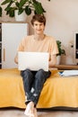 Happy young teenager working on laptop on the couch at home. Royalty Free Stock Photo