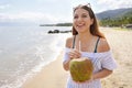 Happy young tourist woman holding green coconut on tropical beach. Summer vacation concept Royalty Free Stock Photo