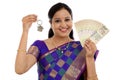 Happy young traditional woman holding Indian currency and house Royalty Free Stock Photo