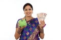 Happy young traditional woman holding Indian currency and piggy Royalty Free Stock Photo