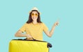 Happy young traveler holding yellow suitcase, smiling and pointing at copy space Royalty Free Stock Photo