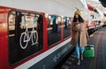 Happy young traveler woman with luggage boarding in the train at train station platform Royalty Free Stock Photo