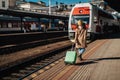 Happy young traveler woman with luggage boarding in the train at train station platform. Rear view. Royalty Free Stock Photo