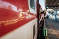 Happy young traveler woman with luggage getting off the train at train station platform Royalty Free Stock Photo