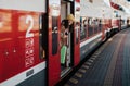 Happy young traveler woman with luggage getting off the train at train station platform Royalty Free Stock Photo