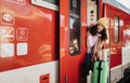 Happy young traveler woman with luggage getting off the train at train station platform Royalty Free Stock Photo