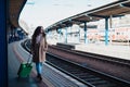 Happy young traveler woman with luggage waiting for train at train station platform Royalty Free Stock Photo