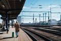 Happy young traveler woman with luggage waiting for train at train station platform Royalty Free Stock Photo