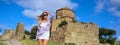 Happy young traveling woman blonde tourist outdoors in ancient Europe fortress ruins. Beautiful female on summer holiday