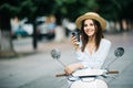 Happy young trendy woman drinking takeaway coffee near her moped in the morning Royalty Free Stock Photo