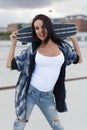 Happy young urban woman posing with longboard behind head Royalty Free Stock Photo