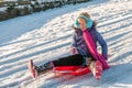 Happy young vibrantly dressed girl sledging with blue ear muffs Royalty Free Stock Photo