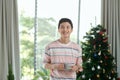 Happy young Vietnamese businessman standing near fir tree, holding coffee cup Royalty Free Stock Photo