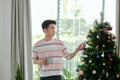 Happy young Vietnamese businessman standing near fir tree, holding coffee cup Royalty Free Stock Photo