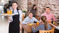 happy young waitress warmly welcoming guests to family cafe Royalty Free Stock Photo