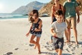 Happy young white family on holiday exploring a beach together, front view, full length, crop