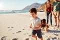 Happy young white family on holiday exploring a beach together, full length, close up