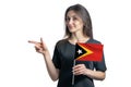 Happy young white woman holding flag East Timor and points to the left isolated on a white background