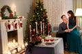 happy young wife sitting on her husband`s knees in a traditionally decorated for Christmas celebration room