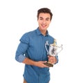 Happy young winner holding his trophy prize and smiles