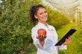 Happy young woman agronomist with red organic apple in her hand Royalty Free Stock Photo