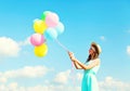 Happy young woman with an air colorful balloons is having fun wearing a summer straw hat over a blue sky background Royalty Free Stock Photo
