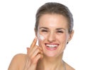 Happy young woman applying creme on face Royalty Free Stock Photo