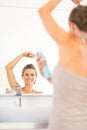 Happy young woman applying deodorant on underarm Royalty Free Stock Photo