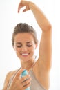Happy young woman applying deodorant on underarm Royalty Free Stock Photo