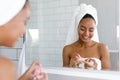 Happy young woman applying face cream in bathroom Royalty Free Stock Photo