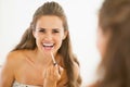 Happy young woman applying lip gloss in bathroom Royalty Free Stock Photo