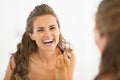 Happy young woman applying lipstick in bathroom Royalty Free Stock Photo