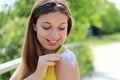 Happy young woman applying sunblock on shouder skin outdoor on a summer day