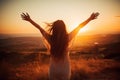 Happy young woman with arms outstretched enjoying the sunset on the mountain, Excited girl standing and celebrating success on a Royalty Free Stock Photo