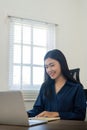 Happy young woman asian working from home distance on laptop taking notes. Smiling business woman lady using computer Royalty Free Stock Photo