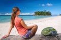 Happy young woman with backpack relaxing on coast and looking to